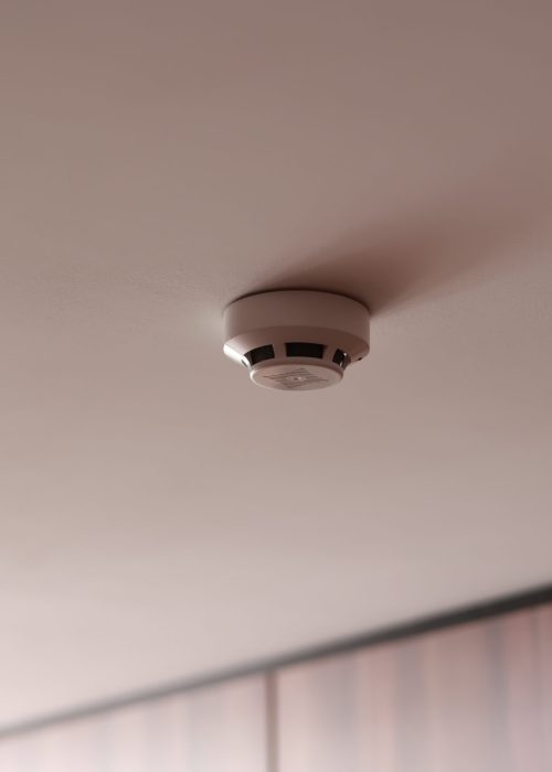 Fire system indoors. White smoke detector issue a signal to a fire alarm control panel as part of a fire alarm system installed on the white ceiling in the office building or apartment