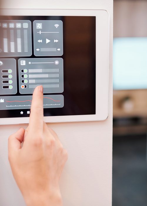 Hand of young woman touching one of digital buttons on smart remote control on the wall